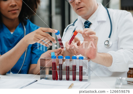 Two scientist or medical technician working, having a medical discuss meeting with an Asian senior female scientist supervisor in the laboratory with online reading, test samples 126659876