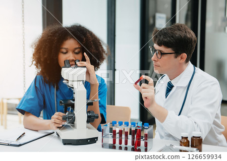 Two scientist or medical technician working, having a medical discuss meeting with an Asian senior female scientist supervisor in the laboratory with online reading, test samples Two scientist or medical technician working, having a medical discuss meeting with an Asian senior female scientist supervisor in the laboratory with online reading, test samples 126659934