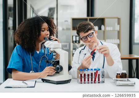 Two scientist or medical technician working, having a medical discuss meeting with an Asian senior female scientist supervisor in the laboratory with online reading, test samples Two scientist or medical technician working, having a medical discuss meeting with an Asian senior female scientist supervisor in the laboratory with online reading, test samples 126659935