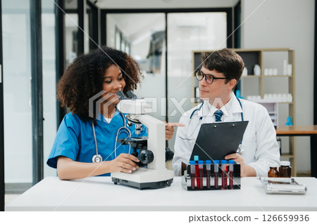 Two scientist or medical technician working, having a medical discuss meeting with an Asian senior female scientist supervisor in the laboratory with online reading, test samples 126659936