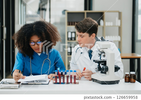 Focused mature male doctor and African female nurse look at tablet and laptop screen discuss anamnesis together. Concentrated diverse medical professionals Focused mature male doctor and African female nurse look at tablet and laptop screen discuss anamnesis together. Concentrated diverse medical professionals 126659958