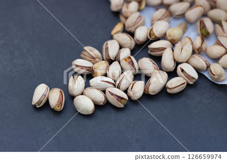 Open pistachio nuts scattered on dark surface Open pistachio nuts scattered on dark surface 126659974
