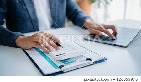 Women counting coins on calculator taking from the piggy bank. hand holding pen working on calculator to calculate on desk about cost 126659976