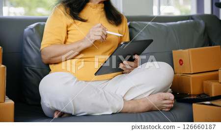 Mature business owner woman prepare parcel box and standing check online orders for deliver to customer on tablet, laptop Shopping Online Mature business owner woman prepare parcel box and standing check online orders for deliver to customer on tablet, laptop Shopping Online 126660187