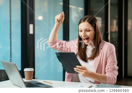 Business expert attractive smiling young woman typing laptop and holding digital tablet 126660360