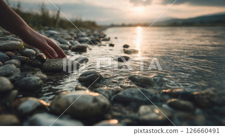 Hand Touching Smooth River Rocks at Sunset 126660491