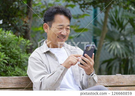 Middle-aged man using a smartphone outdoors Middle-aged man using a smartphone outdoors 126660859