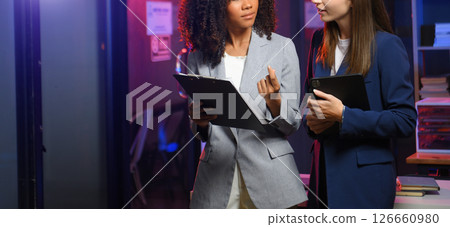 Two business workers talking on the smartphone and using laptop at the office. overtime 126660980