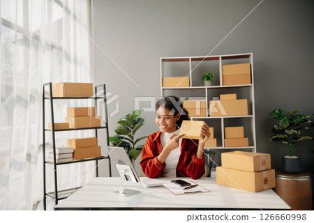 Young African woman prepare parcel box and standing check online orders for deliver to customer on tablet, laptop Shopping Online concept. Young African woman prepare parcel box and standing check online orders for deliver to customer on tablet, laptop Shopping Online concept. 126660998