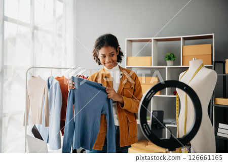 Diverse female fashion designers at work with tailor centimeters on necks and holds tablet and smartphone. independent creative design business. Diverse female fashion designers at work with tailor centimeters on necks and holds tablet and smartphone. independent creative design business. 126661165
