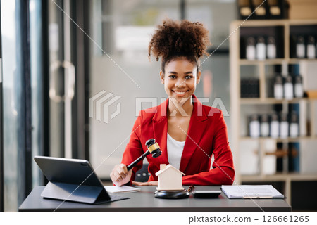 Young real estate agent worker working with laptop and tablet at table in office and small house beside it. 126661265