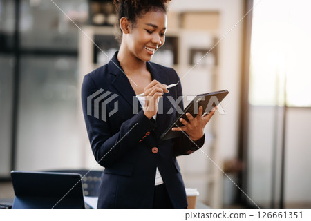 Young attractive Asian female office worker business suits smiling at camera in office Young attractive Asian female office worker business suits smiling at camera in office 126661351