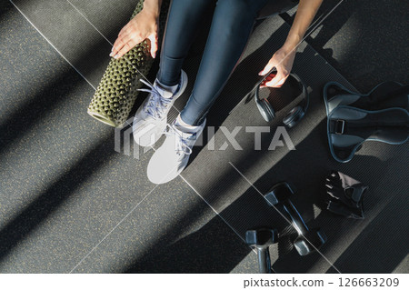 Girl and black dumbbells for sports, ankle weights, headphones, massage roller 126663209