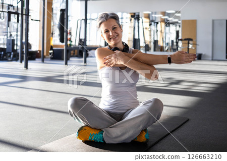 Athletic fitness An elderly gray-haired senior pensioner of age stretching body at gym 126663210