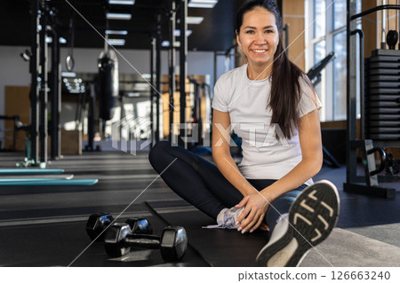 Smiling athletic young Asian woman sport fitness coach posing on mat gym. Smiling athletic young Asian woman sport fitness coach posing on mat gym. 126663240