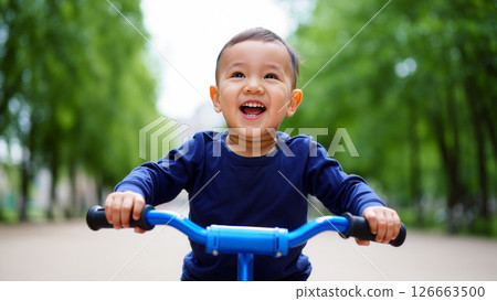 Happy Child Riding a Blue Bicycle Through a Lush Green Park on a Sunny Day 126663500
