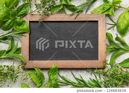 Fresh herbs framing empty chalkboard on gray stone background 126663638