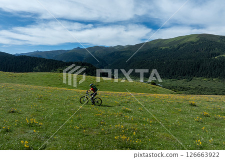 Woman riding mountain bike on beautiful flowering grassland mountain top 126663922