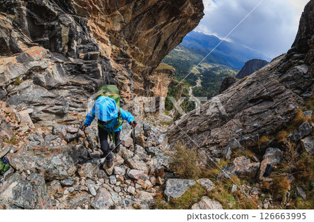Woman backpacker climbing up on steep cliff edge at high altitude mountains top Woman backpacker climbing up on steep cliff edge at high altitude mountains top 126663995