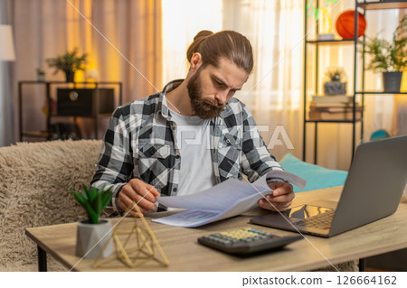 Serious man analyzes contract with a bank at home table clutches head at complex conditions clauses 126664162
