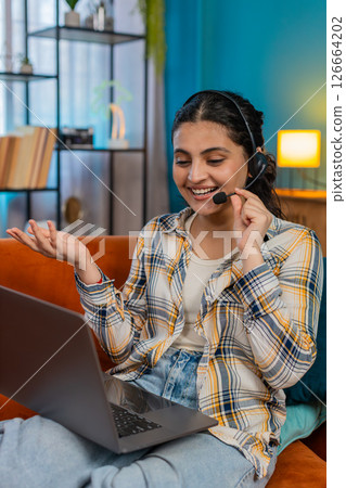 Indian woman call-center operator working home on laptop wearing headset microphone concentrated 126664202