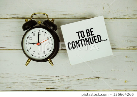 To be continued... text message on sticky note with alarm clock on wooden background 126664266