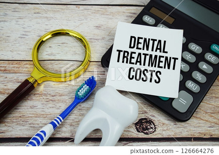 Dental Treatment Costs text with magnifying, toothbrush and calculator on wooden background 126664276