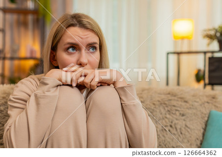 Adult sad woman showing visible stress, tension and emotional irritated, fatigue at home on sofa Adult sad woman showing visible stress, tension and emotional irritated, fatigue at home on sofa 126664362