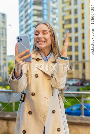 Happy businesswoman using smartphone celebrating victory win message news on downtown city street Happy businesswoman using smartphone celebrating victory win message news on downtown city street 126664394