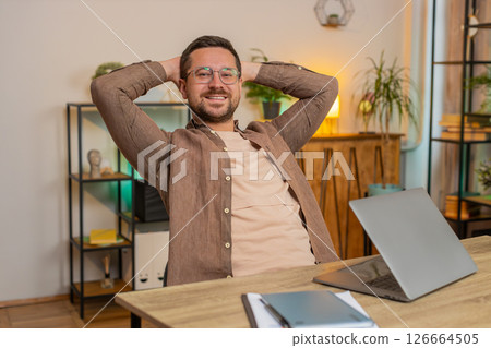 Happy Caucasian young businessman closing laptop after finishing work relaxing at home office desk Happy Caucasian young businessman closing laptop after finishing work relaxing at home office desk 126664505