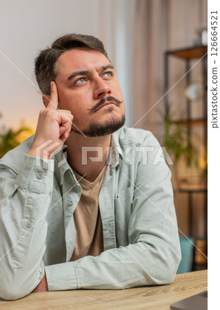 Caucasian Smart focused young man freelancer pensive thoughtful sitting at home office table 126664521
