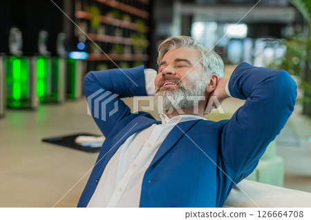 Caucasian businessman taking break leaning on couch after working celebrating success at hotel lobby Caucasian businessman taking break leaning on couch after working celebrating success at hotel lobby 126664708