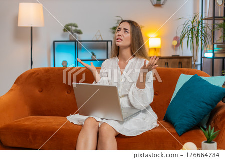 Upset young Caucasian woman using laptop computer having anxiety and stress sitting on sofa at home 126664784
