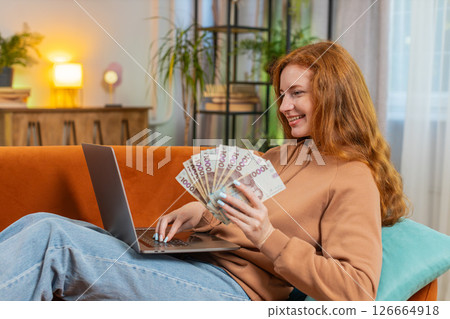 Rich happy woman counting money Ukrainian hryvnias UAH cash using laptop calculate domestic bills Rich happy woman counting money Ukrainian hryvnias UAH cash using laptop calculate domestic bills 126664918