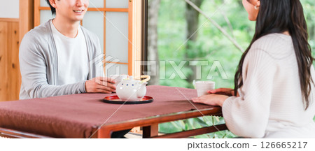 Couple drinking tea in a Japanese-style room at a ryokan with a garden view 126665217