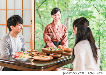 A female inn staff member explaining the dishes in a guest room at a hot spring inn 126665290