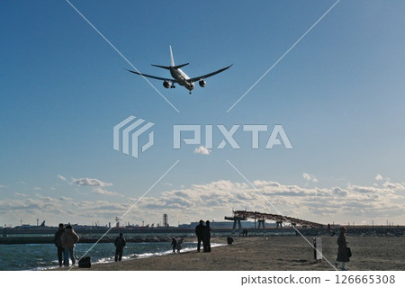 晴朗的冬日，一架客機飛過城南島海濱公園的海灘，駛向羽田機場的 B 跑道 126665308