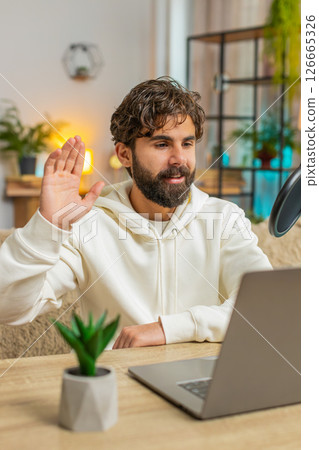 Happy blogger man recording podcast on sofa couch, giving workshop, webinar sitting on sofa at home 126665326