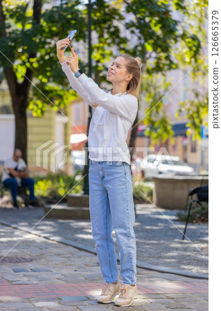 Young female tourist trying to catch a communication signal and Internet on cellphone in city street 126665379