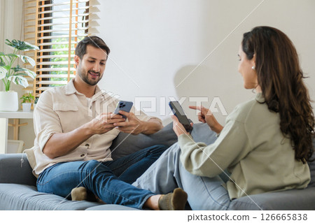 Hispanic Couple sitting together but emotionally distant, ignoring each other while using smartphones and social media at home Hispanic Couple sitting together but emotionally distant, ignoring each other while using smartphones and social media at home 126665838