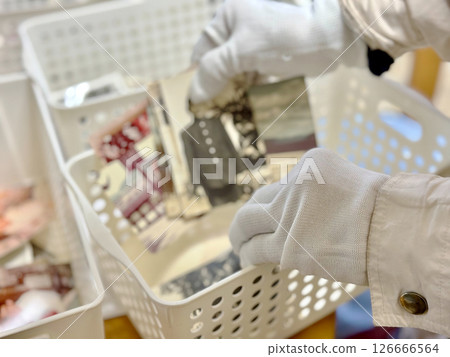 White-gloved hands putting black-and-white photographs into a case White-gloved hands putting black-and-white photographs into a case 126666564