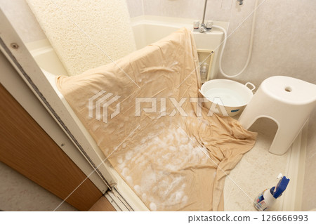 Washing the futon cover in the bathtub. The mattress is propped up in the bathtub. 126666993