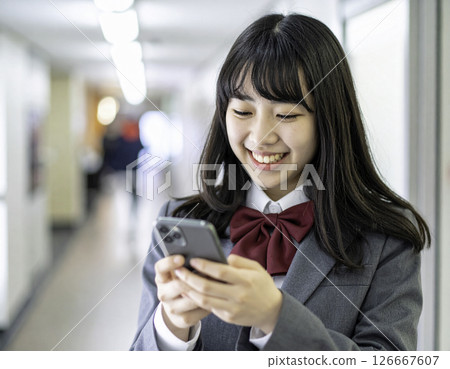 A high school girl smiling while using her smartphone | A scene from the school building on the way to school 126667607