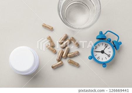 Supplement, vitamin capsule with medical bottle and clock on beige background, nutrition and healthy lifestyle 126669441
