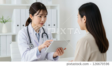 A doctor explaining something to a patient using a tablet during an examination 126670596