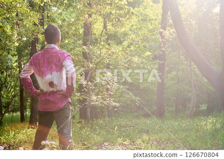 一名男子站在霧氣瀰漫的樹林中,樹上的嫩葉在陽光下閃閃發光 一名男子站在霧氣瀰漫的樹林中,樹上的嫩葉在陽光下閃閃發光 126670804