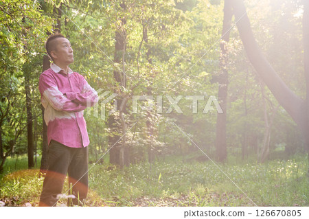 A man stands in a misty grove with young leaves shining in the sunlight 126670805