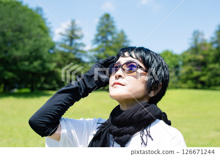 一位中年婦女戴著太陽眼鏡、圍巾和手套保護自己免受紫外線的傷害 一位中年婦女戴著太陽眼鏡、圍巾和手套保護自己免受紫外線的傷害 126671244