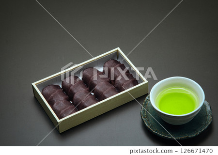 享用這款美味的日本糖果，它由柔軟的麻糬包裹在光滑的豆沙中，並配上一些日本茶。 126671470