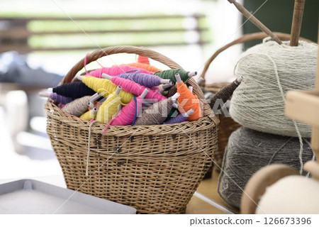 Handweaving Yarn Spools in Wicker Basket Handweaving Yarn Spools in Wicker Basket 126673396